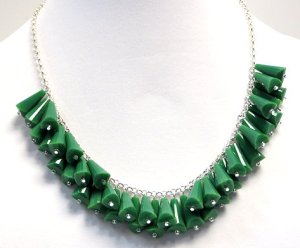 These green components, in the piece shown above, are made out of Chinese crystal, not plastic.     To the naked eye, you might see a similar piece where the components are plastic, looking like but definitely not crystal.   The eye can deceive itself.   Simple test: click bead against a stiff surface or front teeth.   If crystal or glass, you will hear a sharp click; if plastic, you will hear a dull click.